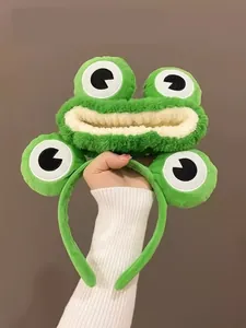 Gros plan sur un bandeau grenouille en peluche verte avec de grands yeux de dessin animé
