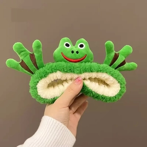 Détail d'un bandeau en peluche grenouille verte montrant la doublure douce et la broderie
