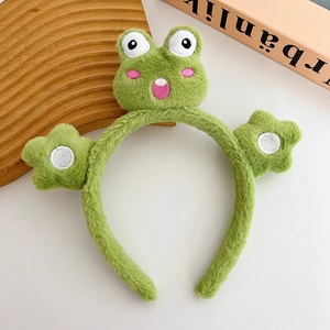 Dettaglio della fascia in peluche verde a forma di rana con ricami e stelle carine