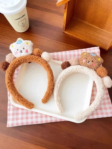Detail eines weichen Teddybär-Haarreifens in Braun und Beige mit bunten Plüschkugeln