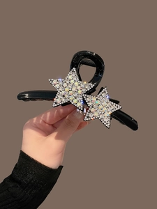 Détail macro d'une pince à cheveux noire avec des étoiles brillantes serties de strass