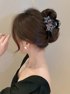 Détail d'une grande pince à cheveux noire ornée d'étoiles scintillantes en strass bleus