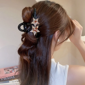 Pince à cheveux étoile ornée de strass multicolores sur une base en acrylique noir