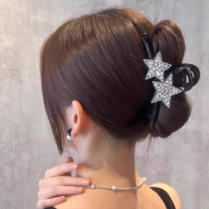 Détail de la pince à cheveux noire élégante avec des décorations d'étoiles en strass
