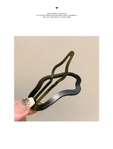 Dettaglio di un fermaglio per capelli in metallo ondulato nero tenuto da una mano