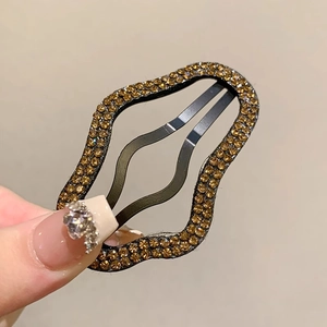 Dettaglio di un fermaglio per capelli ondulato con strass color ambra lucidi
