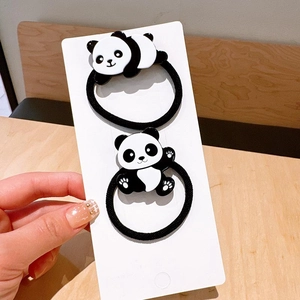 Detail view of two cute panda hair ties on a card, showing sitting and crawling poses