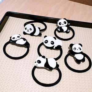 Detailed view of six cartoon panda hair ties with various poses on a woven display tray