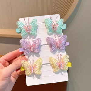 Detailed close-up of six embroidered butterfly hair clips with pearls on display card