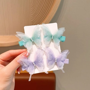 Detail of four butterfly hair clips with embroidery, sheer mesh wings, and white pearls