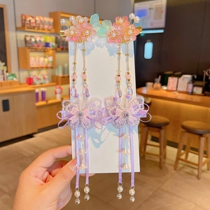 Détail de pinces à fleurs en résine rose avec nœuds en tulle violet et longs glands perlés