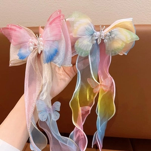 Détail de nœuds papillon dégradés avec longs rubans en organza et perles pour filles