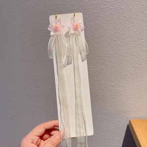 Detail of pink fabric flowers and long white mesh tassels on elegant drop earrings