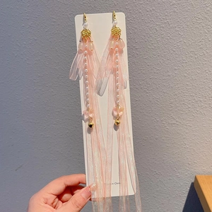 Detail of pink tassel earrings for girls with floral accents and faux pearl beads