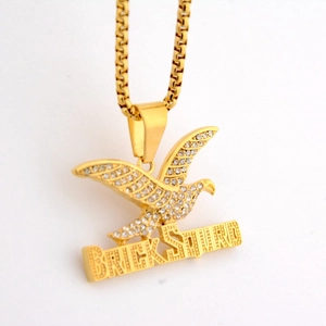 Macro shot of gold hip hop eagle pendant with BRICK SQUAD letters and rhinestones