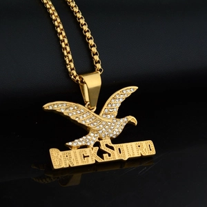 Hip hop style gold eagle pendant with BRICKSQUAD crystals on black leather background