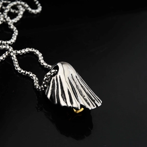 Vue macro du pendentif aile argentée avec détail doré sur fond noir réfléchissant