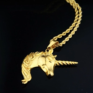 Collier avec pendentif licorne dorée et chaîne torsadée sur fond noir poli