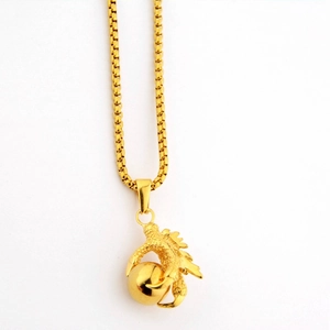 Gros plan du pendentif griffe de dragon dorée avec une perle et sa chaîne à mailles