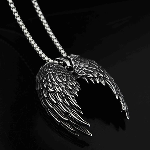 Gros plan du pendentif ailes d'ange en argent avec texture de plumes sur fond noir