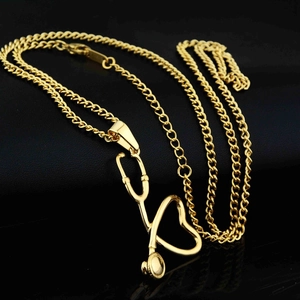 Vue macro d'un pendentif stéthoscope doré avec chaîne gourmette sur fond de cuir noir