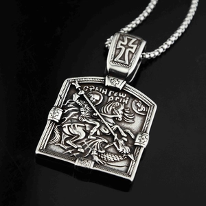 Détail du relief de Saint Georges et le dragon sur un pendentif vintage en acier