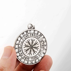 Détail d'un pendentif viking Vegvisir argenté avec des runes et texte gravé