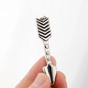 Gros plan d'un pendentif flèche en acier titane argenté avec texture plume et aspect vintage