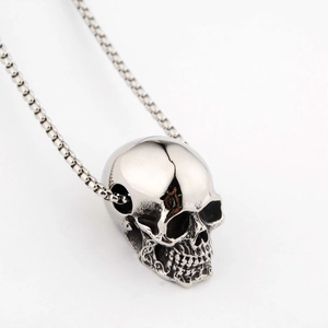 Close-up of vintage silver skull pendant with detailed metallic texture and box chain