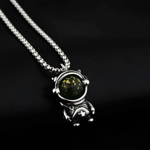 Pendentif astronaute argenté avec casque étoilé vert sur fond en cuir noir élégant