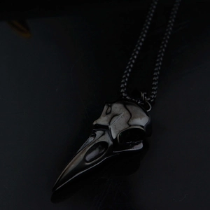 Détail macro d'un pendentif crâne de corbeau gothique sur une longue chaîne en acier inoxydable