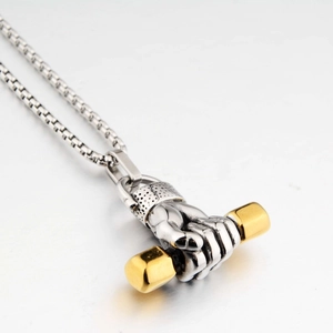 Detailed close-up of a silver barbell pendant with gold accents on a steel box chain