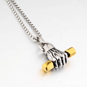 Macro shot of silver fist holding a golden barbell pendant on a stainless steel box chain