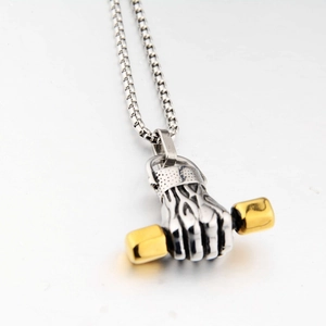 Detailed close-up of a silver fist pendant holding a golden barbell on a box chain