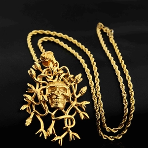 Dettaglio del ciondolo a teschio Medusa dorato con serpenti su pelle nera