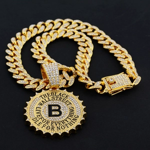 Macro shot of gold hip hop pendant with B-letter and engraved motivational quotes