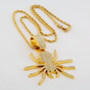 Détail du pendentif araignée dorée orné de cristaux blancs sur une chaîne torsadée d'or