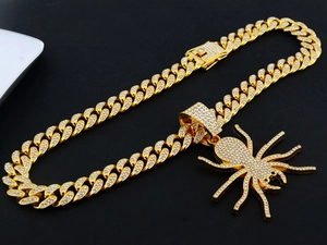 Détail du pendentif araignée dorée serti de strass avec chaîne à mailles cubaines