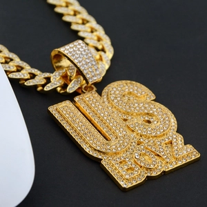 Close-up of iced out US BOYZ pendant with micro paved rhinestones on gold Cuban chain