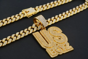 Macro shot of gold Cuban chain and US BOY pendant with sparkling rhinestones