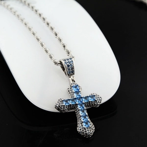 Détail du pendentif croix en argent serti de zircons bleus avec chaîne torsadée