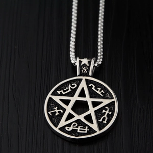 Detailed close-up of a vintage steel pentagram pendant with ancient rune engravings