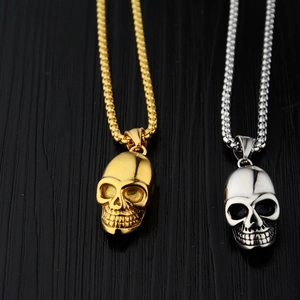 Colliers pendentifs tête de mort en acier inoxydable poli or et argent sur fond sombre