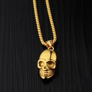 Collier avec pendentif crâne doré poli et chaîne vénitienne sur fond de bois sombre