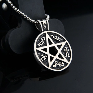 Macro shot of vintage titanium steel pentagram pendant with rune engravings on black