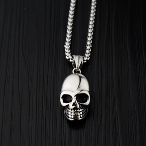 Collier avec pendentif crâne en acier inoxydable poli et chaîne à billes sur bois noir