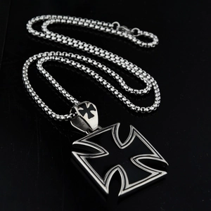 Detail of silver and black stainless steel Maltese cross pendant on a box chain