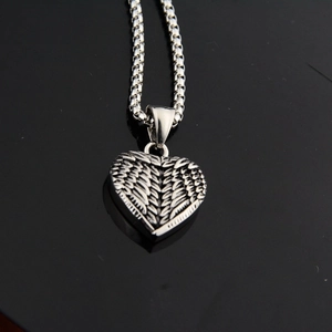 Détail du pendentif cœur vintage avec ailes de plumes sur collier chaîne en argent