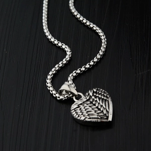 Détail du collier pendentif en forme d'aile de cœur avec texture de plumes en argent