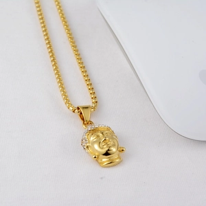 Macro detail of gold Buddha head pendant with sparkling rhinestones and box chain necklace
